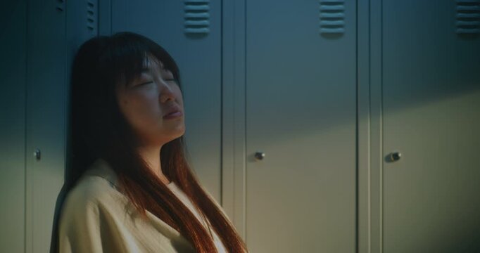 Exhausted Young Woman Leaning against Lockers, Lost in Thought While Coping with Pressure and Emotional Fatigue. Concept of Mental Health, Stress, Burnout, Resilience and Everyday Challenges.