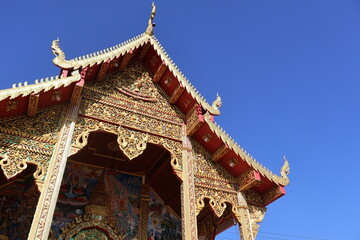 Fototapeta premium Traditional Thai temple structures and ornate details at Wat Phra That Doi Kham in Chiang Mai. Perfect for travel photography, cultural projects, and designs highlighting the rich religious art.