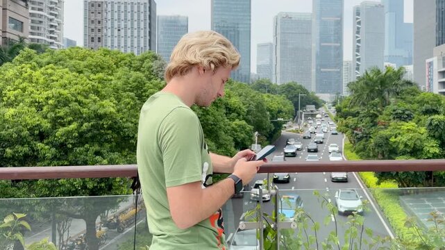 Young Man Using Smartphone Against Skyscrapers &ndash; Talking, Scrolling or Recording Video