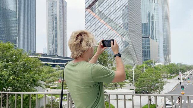 Young Man Using Smartphone Against Skyscrapers &ndash; Talking, Scrolling or Recording Video