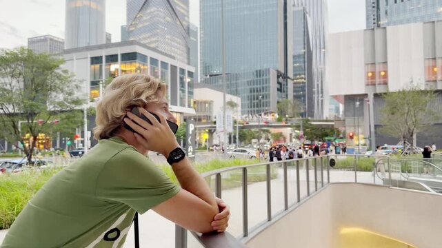 Young Man Using Smartphone Against Skyscrapers &ndash; Talking, Scrolling or Recording Video