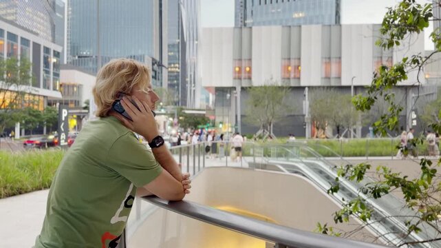 Young Man Using Smartphone Against Skyscrapers &ndash; Talking, Scrolling or Recording Video