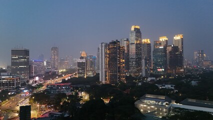 Aerial drone view of Jakarta's Sudirman business district at night featuring illuminated skyscrapers, glowing office buildings, vibrant city lights, and heavy traffic after office hours, showcasing th © rifnaldi