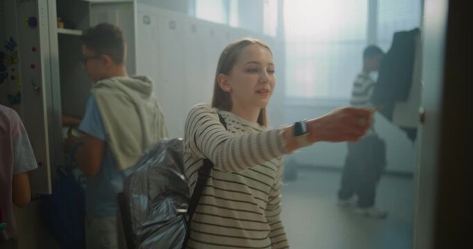 Teenage Girl Enters School Locker Room, Greets Classmates, Places Belongings in Personal Locker. Student Interaction, Friendship, School Community, Positive Social Atmosphere of Everyday Campus Life.