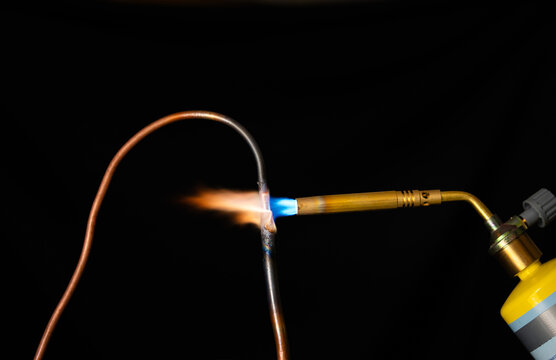 Close-up of a plumber brazing copper pipe with a propane gas torch