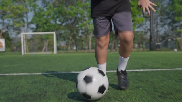 Soccer player dribbling ball outdoor grass field during training, athletic motion blur, goal frame and trees background, dynamic competitive energy natural daylight with focused match preparation