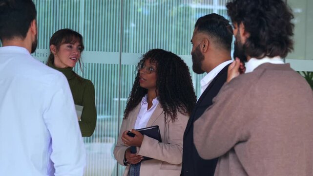 Group of multi-ethnic colleagues standing and talking together during a break in an office building.