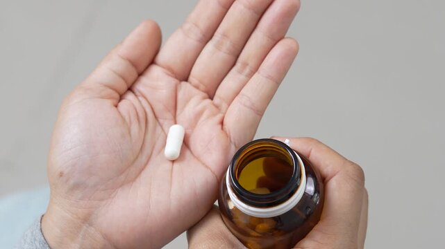 close up hand holding a medicine, with pours the pills out medicine bottle. Stop drug use Taking Medication Caring for the health care medical concept.