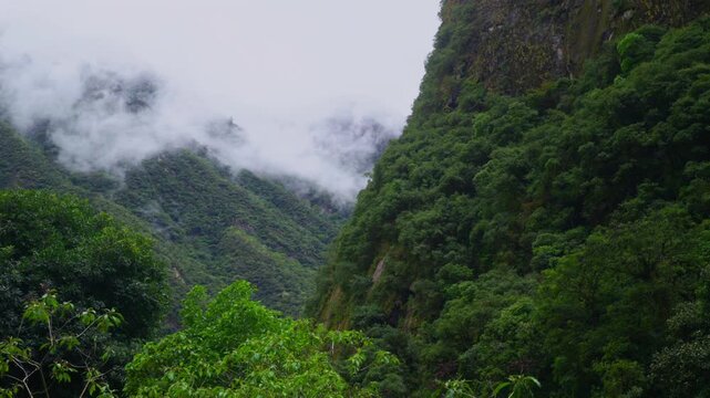 Rainy Aguas Calientes town Machu Picchu entrance jungle lowers highlands dry rainy season cloudy rainy morning Peru Peruvian Andes Mountains Inca trail citadel hotels landscape pan left motion