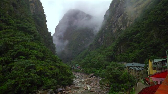 Rainy Aguas Calientes town Machu Picchu entrance Amazon Urabumba river dry rainy season morning Peru Peruvian Andes Mountains jungle lower highlands Inca trail citadel hotels landscape pan left