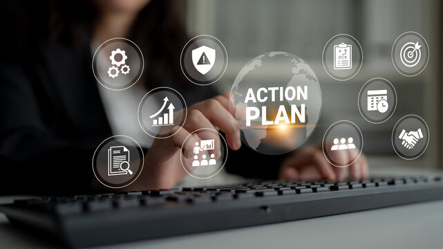 A business professional develops an action plan using strategic icons while working at a keyboard, showcasing collaboration and goal-oriented planning in a modern workspace. Ledger