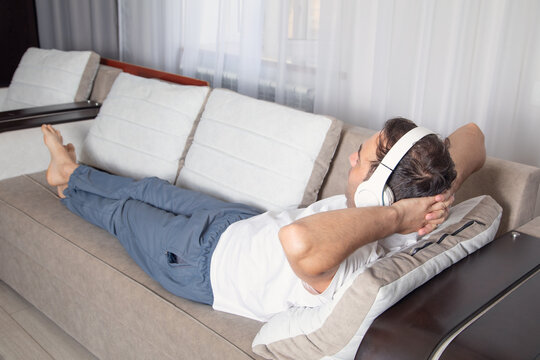 Man with a headphones lying in sofa.