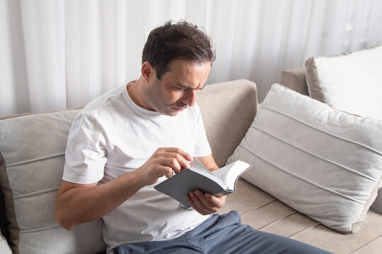 Caucasian man reading book at home.