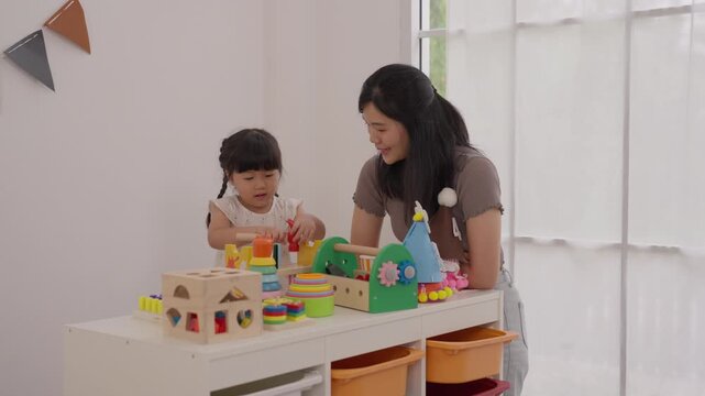Asian mother, daughter, child, family playing with colorful wooden toy at home, learning activity beside bright window, joyful creativity, puzzle, blocks, indoor playroom, shared family time