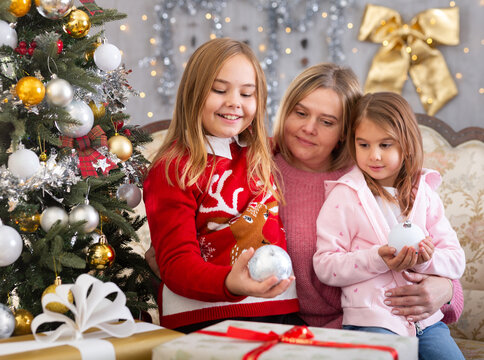 Mom with two daughters hugging in Christmas interior