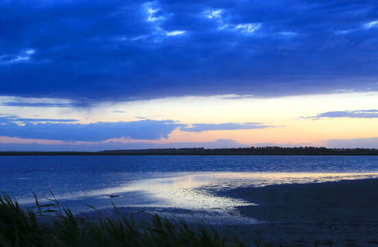 Dramatic twilight sky over a calm lake with reflections and reeds