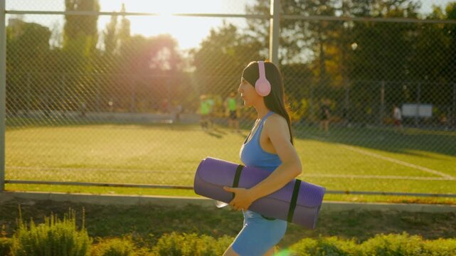 Athletic young girl walking past the park fence before outdoor fitness.