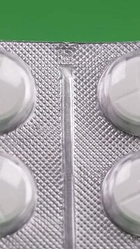 A close-up view of white pills in a blister pack on a green background