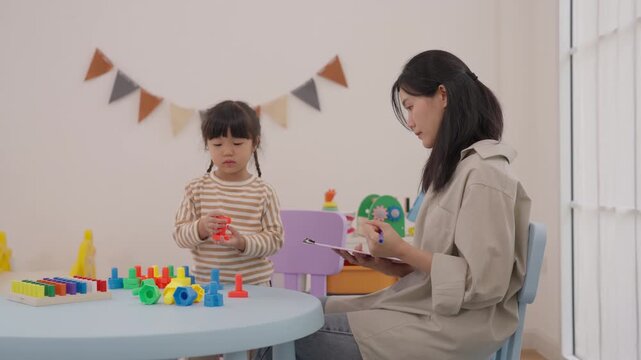 Mother and daughter play with colorful building blocks, child family education activity using toy pieces and worksheet, indoor creativity learning with caregiver and vdo book in bright room