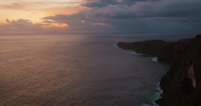 Dark clouds gather over coastal cliffs of Nusa Penida Island during sunset Bali