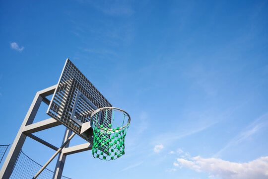 Close-up of an outdoor basketball hoop with a blue sky.