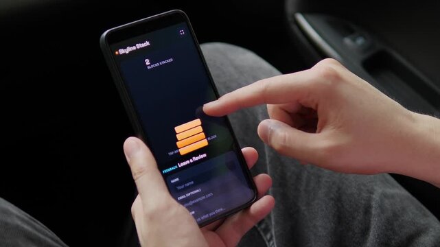 Person builds a virtual tower in a smartphone stacking game, capturing precision, timing, concentration and the addictive challenge of casual mobile entertainment.