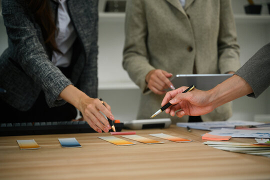 Close up of Business team reviewing color swatches and design samples during creative meeting at office desk
