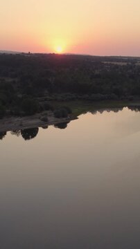 Scenic aerial drone view of La Cuerda del Pozo Reservoir in Spain during a stunning sunset with calm water reflection