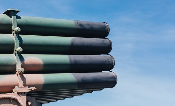 Camouflaged Multiple Rocket Launcher Tubes in Close-Up Against Blue Sky with Copy Space