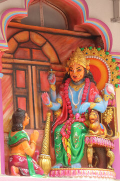 Stone wall relief carving of Lord Narasimha sitting on a throne and blessing the devoted boy Prahlada.
