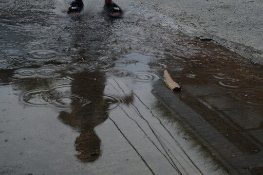 Rain ripples on a puddle with reflection
