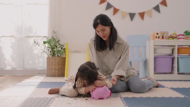 Asian mother and girl playing with pink toy on colorful foam mat in bright home playroom, warm family moment with indoor plant, storage shelf, gentle connection, joyful expression