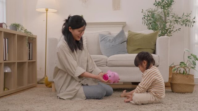 Asian mother, toddler, child, family play with pink toy in cozy living room at home, sitting together on carpet, creating warm bonding moments through joyful indoor activities