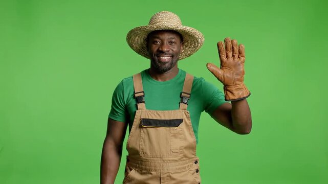 Mid-shot of man waving in green studio background