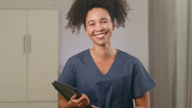 Smiling Black Woman Nurse With Natural Hair Holding a Digital Tablet in a Healthcare Setting