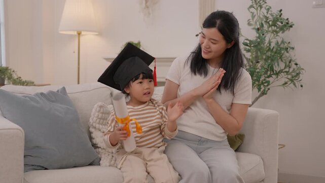 Mother and child celebrate graduation diploma at home, sharing family celebration, education milestone, joyful pride, tender living room moment together on comfortable sofa with warmth
