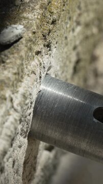 Construction drill bit cutting into a solid rock surface during a building renovation project. Macro close-up shot.