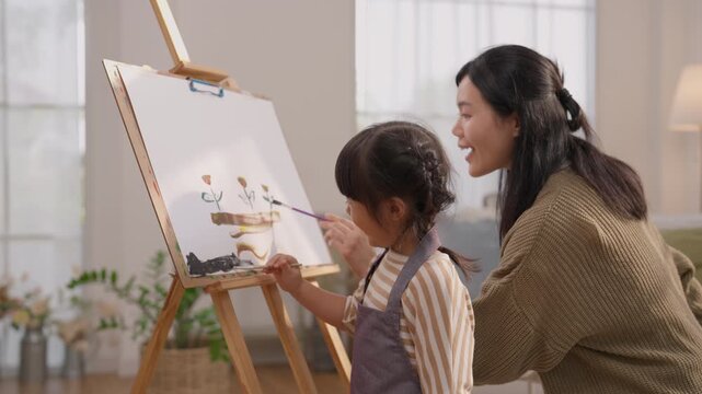 Mother and daughter painting colorful artwork together at home, sharing creativity through brushstrokes on canvas and easel, building joyful family connection with warm creative art activity