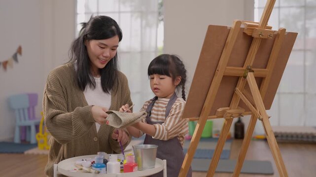 Mother Daughter Painting at Home with Easel and Art Supplies, Creative Family Activity with Child, Woman and Clay Sculpture, Joyful Art Moment Supporting Creativity in Bright Room