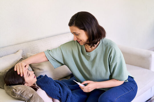 Parental care and concern for a sick child, mother checking daughter's fever at home, family healthcare and wellness