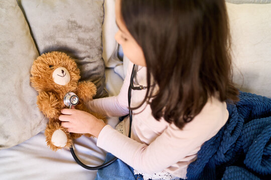 Child playing doctor with teddy bear, pediatric care and imaginative play, home healthcare and wellness