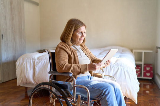Senior woman in wheelchair using digital tablet for telemedicine, home healthcare and independent living for elderly