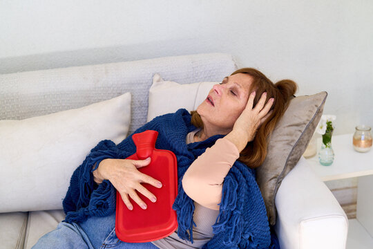 Elderly woman with stomach pain and discomfort, home healthcare and senior care, hot water bottle for relief and recovery at home