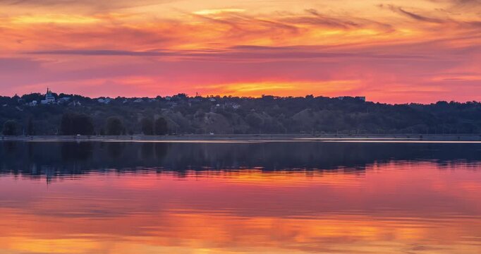 Sunset over the Kyiv Reservoir, with golden sunlight reflecting on calm water and a dramatic cloudy sky. A peaceful summer landscape near Kyiv, Ukraine.