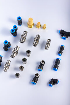 High angle view of various industrial pneumatic push-in fittings and sintered brass silencer mufflers arranged on a white background.