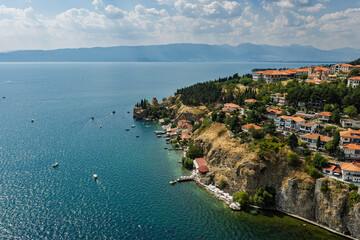 Fototapeta premium Aerial drone view of Ohrid in North Macedonia during summer, featuring historic old town, Kaneo Church, UNESCO heritage landmarks, harbor and crystal clear Lake Ohrid surrounded by scenic landscape