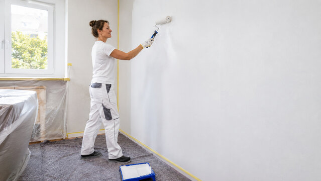Malerin streicht eine Wand in einer renovierten Wohnung