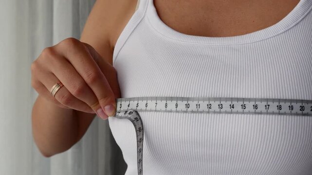 Close-up of woman measuring bust with tape for body measurements and clothing size.