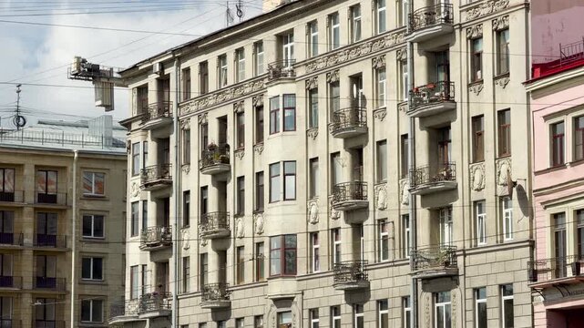 Classic residential buildings stand proudly along a historic street in Saint Petersburg. Ornate balconies and windows line the facade. This grand architecture fills viewers with calm wonder.