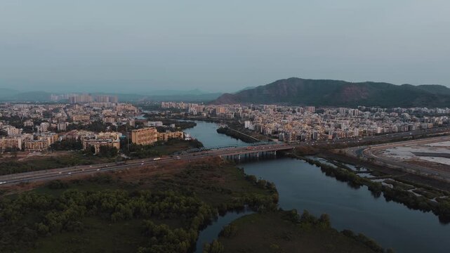 Aerial view of Navi Mumbai showcasing modern highways, bridges, urban development, water bodies, and scenic hills in the background. The image highlights the blend of modern infrastructure.